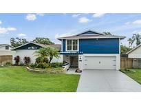 Charming two-story home with a vibrant blue accent and lush landscaping at 15609 Gardenside Ln, Tampa, FL 33624
