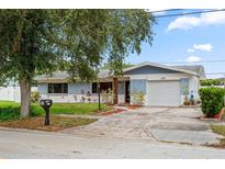 Charming single-story home with a well-maintained lawn, blue accents and a single car garage at 1579 Palmetto St, Clearwater, FL 33755