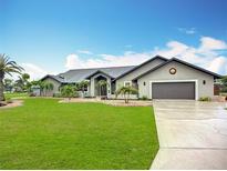 Charming single-story home features a well-manicured lawn, lush landscaping, and a neutral color palette at 27466 Tierra Del Fuego Cir, Punta Gorda, FL 33983