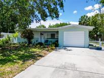 Charming single-story home with a well-manicured front yard, a white picket fence and attached one car garage at 5600 Hobson Ne St, St Petersburg, FL 33703