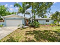 Charming single-story home featuring a lush landscaped front yard with mature palm trees and an attached garage at 5961 36Th Ave N, St Petersburg, FL 33710
