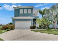 Two-story home featuring a white garage door, second story balcony, and landscaping at 6512 Simone Shores Cir, Apollo Beach, FL 33572