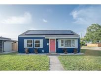 Charming blue home with solar panels, a pink door, and well-manicured lawn at 1001 57Th N Ave, St Petersburg, FL 33703