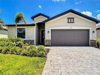 Charming home featuring a two-car garage, stone accents, lush landscaping, and inviting curb appeal at 11100 Balfour St, Venice, FL 34293