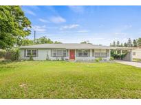 Charming single-story home with a well-maintained lawn, complemented by a red front door and a convenient carport at 1607 Bell Shoals Rd, Brandon, FL 33511