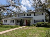 Charming two-story home with a manicured lawn, a red door and mature trees at 210 Kingsway Dr, Temple Terrace, FL 33617