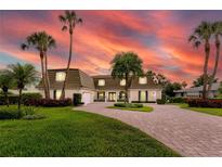 Stunning two-story home featuring lush landscaping, brick driveway, and elegant architectural details during a beautiful sunset at 224 Harbor View Ln, Largo, FL 33770
