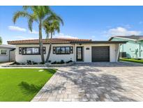 Charming single-story home with a well-manicured lawn, paver driveway, and beautiful landscaping at 241 176Th Terrace E Dr, Redington Shores, FL 33708