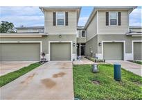 View of townhomes with light exteriors and single-car garages, accented with landscaping at 2844 Jacob Crossing Ln, Holiday, FL 34691