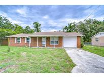 Charming brick home featuring a well-maintained lawn and a one-car garage at 40019 Pretty Redbird Rd, Zephyrhills, FL 33540