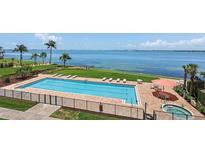 Community pool with ocean view, lounge chairs, and adjacent spa at 4953 Bacopa S Ln # 205, St Petersburg, FL 33715