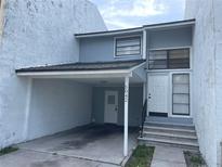 Two-story townhome featuring a carport, neutral paint, front door access, and natural light at 5042 Terrace Village Ln, Tampa, FL 33617