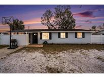 Charming single-story home at dusk with a basketball hoop and fenced yard, offering comfortable living at 8401 Pinewood St, Tampa, FL 33615