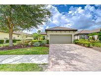 Charming home featuring a tile roof, two-car garage, brick paver driveway, and well-maintained landscaping at 8433 Alberata Vista Dr, Tampa, FL 33647