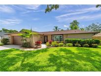 Charming single story home with a manicured lawn and colorful landscaping at 11245 Bella Loma Dr, Largo, FL 33774