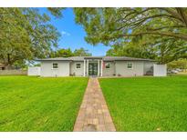 Charming one-story home features a lush lawn, stone walkway, and inviting entrance with large shade trees at 1641 Jeffords St, Clearwater, FL 33756