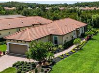 Charming home featuring a clay tile roof, manicured lawn and elegant landscaping at 20025 Callisto Hill Pl, Tampa, FL 33647