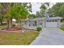 Charming home with a gray brick facade, a front porch, well-kept lawn, and mature landscaping at 215 Claire Dr, Seffner, FL 33584