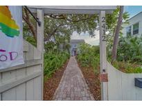 Inviting walkway leading to a charming home, framed by lush greenery and an arbor with visible address at 2412 Burlington N Ave, St Petersburg, FL 33713