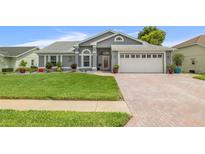 Charming single-story home with a well-manicured lawn, brick driveway, and attached two-car garage at 8441 Danbury Ln, Hudson, FL 34667