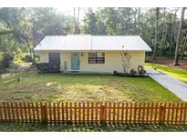 Charming single-story home with metal roof, tidy lawn, and a decorative picket fence at 10804 Bounty St, New Port Richey, FL 34654