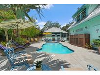 Backyard pool area framed by mature trees, comfortable lounge chairs, and shade umbrellas at 111 29Th W St, Bradenton, FL 34205