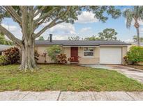 Charming single story home with beautiful landscaping, a red front door, and attached garage at 11320 125Th Ter, Largo, FL 33778