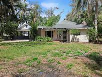 Charming single-story home with a quaint carport surrounded by lush, mature trees and greenery at 17306 Livingston Ave, Lutz, FL 33559