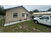 Tan, single-story home featuring a cozy front yard and a covered carport with a white truck at 18133 Us Highway 41, Spring Hill, FL 34610