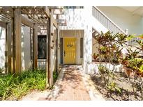Charming entryway with a bright yellow door, brick walkway, and pergola, creating a welcoming facade at 1854 Lake Cypress Dr # 1854, Safety Harbor, FL 34695