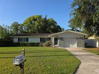 Charming single-story home with a well-maintained lawn and lush greenery at 2045 Summit Dr, Dunedin, FL 34698