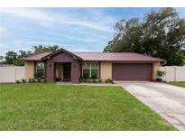 Charming single-story home featuring a well-manicured lawn and a lovely brown metal roof at 3509 King George Ln, Seffner, FL 33584