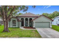 Charming single-story home featuring a well-manicured lawn, attached garage, and inviting curb appeal at 5809 Silas Creek Ln, Wesley Chapel, FL 33545