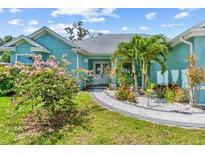 Charming blue single-story home featuring a paved walkway and lush landscaping with palm trees at 716 Laurel Ave, Venice, FL 34285