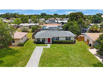 Charming single-story home featuring a red front door, green lawn, and meticulously manicured landscaping at 8339 75Th Ave, Seminole, FL 33777