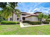Stately home featuring a meticulously manicured front lawn, terracotta tile roof, and mature palm trees enhancing curb appeal at 9827 Sorbonne Loop, Seffner, FL 33584
