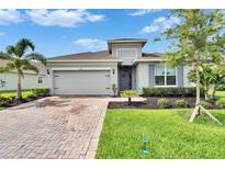 Charming one-story home featuring a brick driveway and a lush, landscaped front yard at 11785 Little River Way, Parrish, FL 34219