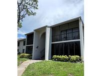 Condo exterior showcasing well-maintained landscaping and screened-in balconies for outdoor enjoyment at 2699 Pine Ridge E Way # H2, Palm Harbor, FL 34684
