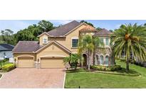 Stunning two-story home with a three-car garage, brick driveway, mature landscaping, and a turret-style entry at 3148 Watermark Dr, Wesley Chapel, FL 33544