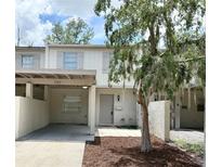 Charming townhouse featuring a covered parking area and a quaint front entrance with a tree in the landscaped yard at 5229 Tennis Court Circle, Tampa, FL 33617