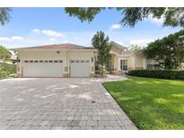 Charming home featuring a three-car garage, stone accents, a brick driveway, and well-manicured lawn at 10310 Carroll Cove Pl, Tampa, FL 33612