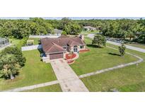 Inviting single-Gathering home features a well-manicured lawn and an attached two-car garage at 13386 Lawrence St, Spring Hill, FL 34609