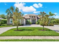 Charming single-story home featuring lush landscaping, a paver driveway, and a welcoming double-door entrance at 15415 Mulholland Rd, Parrish, FL 34219