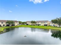 Scenic view of the back of townhomes overlooking a serene lake with lush green surroundings at 6706 47Th N St, Pinellas Park, FL 33781
