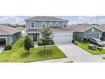 Two-story home features a light-blue facade, a two-car garage, and a well-manicured lawn at 8576 Broadstone Dr, Wesley Chapel, FL 33544