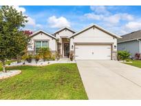 Beautiful single-story home with a manicured lawn, white rock garden, and neutral color palette at 944 Old Windsor Way, Spring Hill, FL 34609