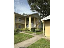 Inviting two-story condo featuring well-maintained landscaping, a sidewalk, and convenient stair access to all units at 1408 Millstream Ln # 206, Dunedin, FL 34698