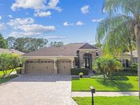 Charming single-story home featuring a three-car garage, brick driveway, and lush landscaping at 16248 Ivy Lake Dr, Odessa, FL 33556
