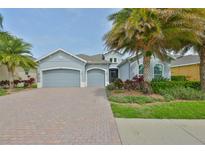 Charming home featuring a three-car garage, beautiful landscaping, and a brick driveway for added curb appeal at 1723 Pacific Dunes Dr, Sun City Center, FL 33573