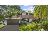 Charming home showcasing lush landscaping, a gray roof, and an attached two-car garage at 208 Live Oak Ln, Largo, FL 33770